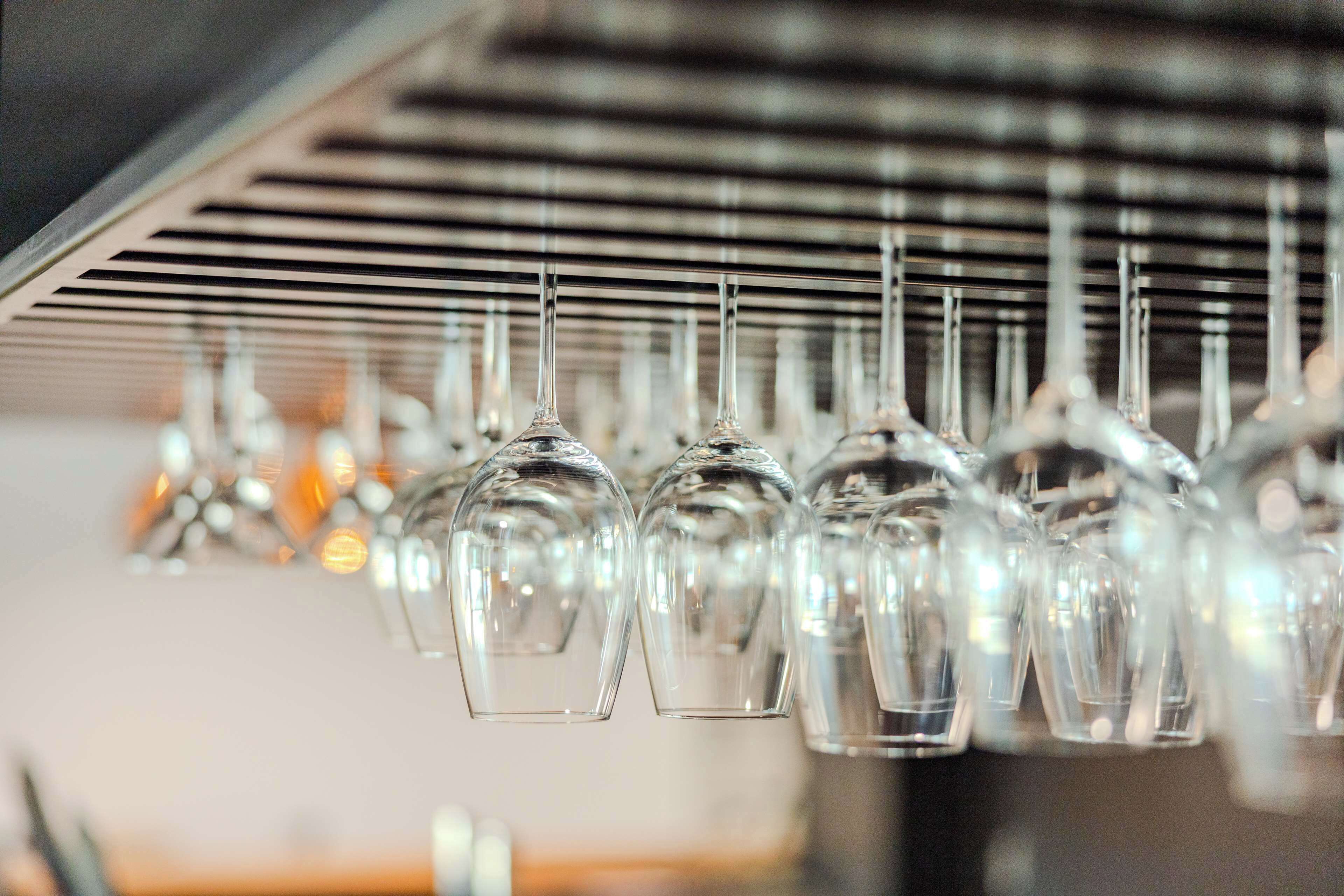 A row of wine glasses hanging from a metal rack.
