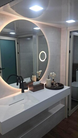 A modern bathroom with a large mirror, a sink, and a towel rack.