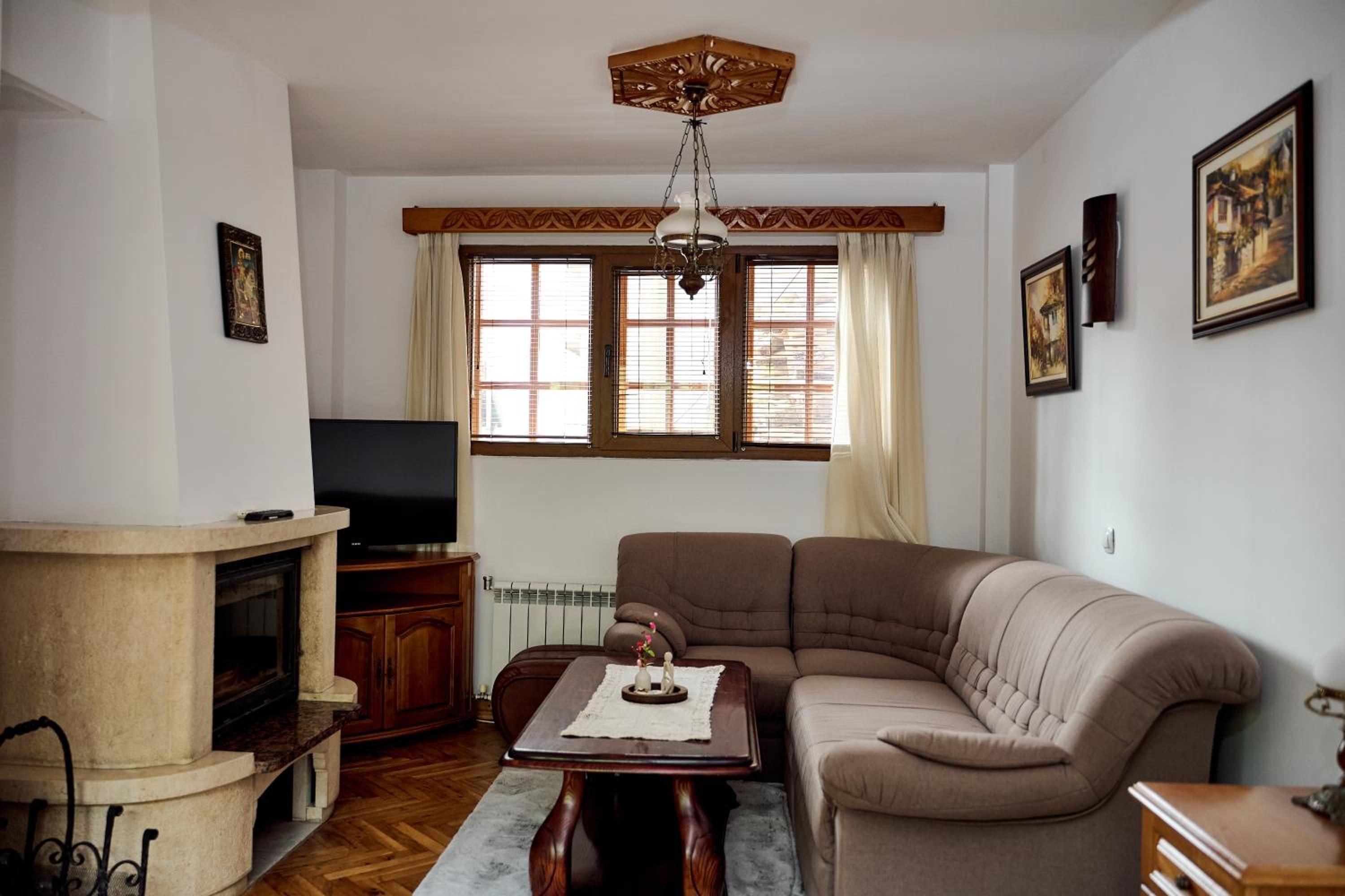 Una sala de estar con sofá, televisión, chimenea y una ventana con persianas.