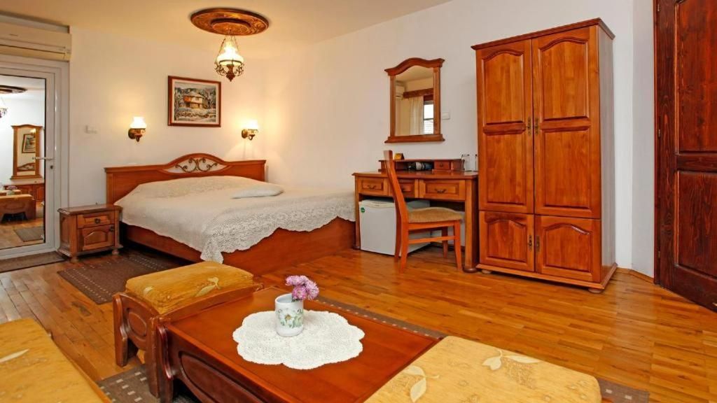 A bedroom with a bed, bedside table, dresser, and a mirror.