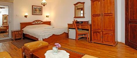 A bedroom with a bed, bedside table, dresser, and a mirror.