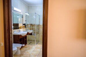 A bathroom with two sinks, a toilet, and a shower enclosure.