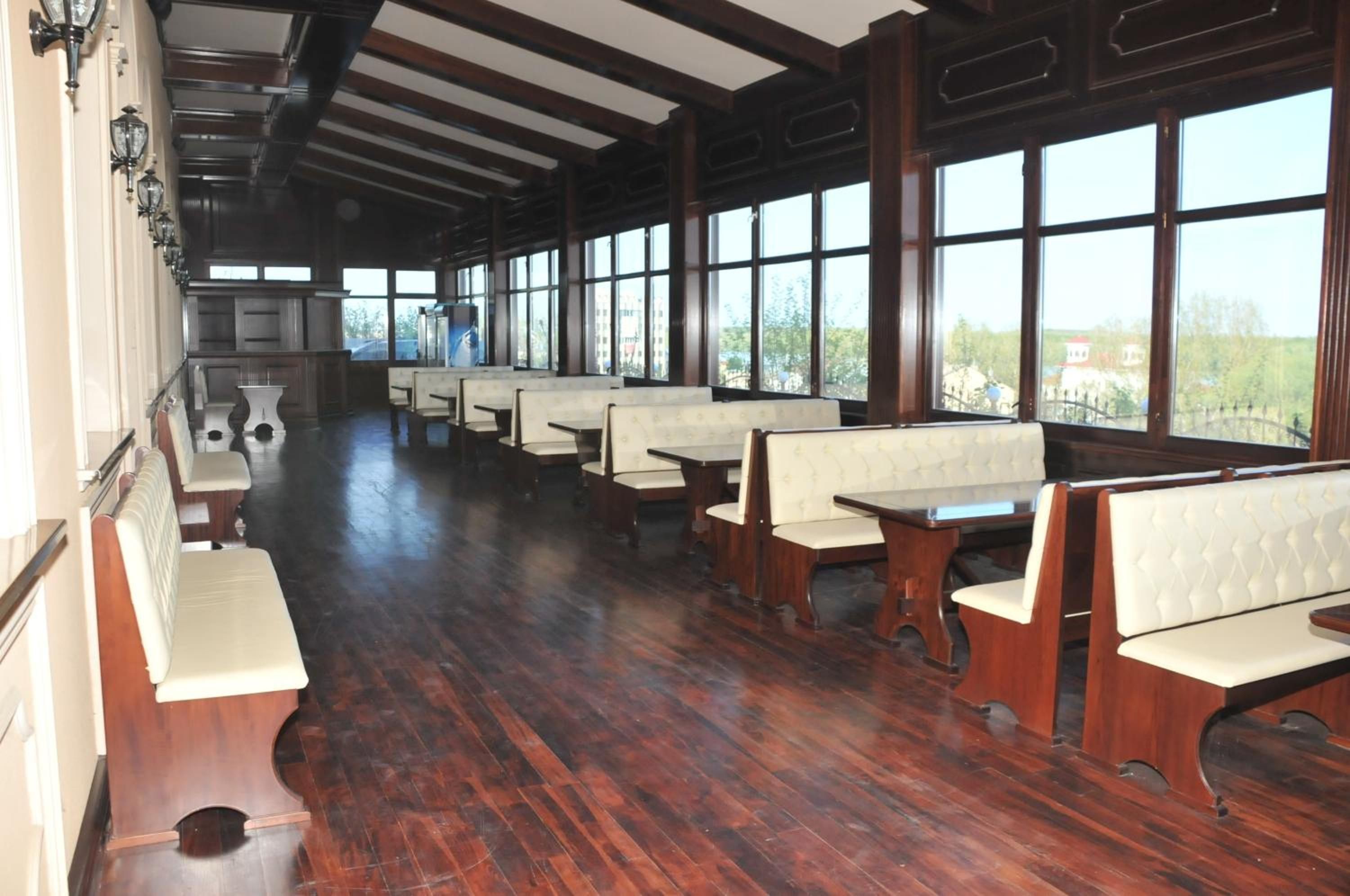 Un comedor amplio con piso de madera y ventanas grandes que ofrecen vistas al exterior.