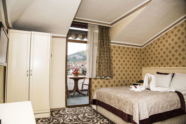 A hotel room with a bed, a wardrobe, a table with chairs, and a view of a mountain. - Nazar Hotel (Trabzon)
