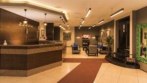 A hotel reception area with a reception desk, seating area, and a staircase leading to an upper floor. - Nazar Hotel (Trabzon)