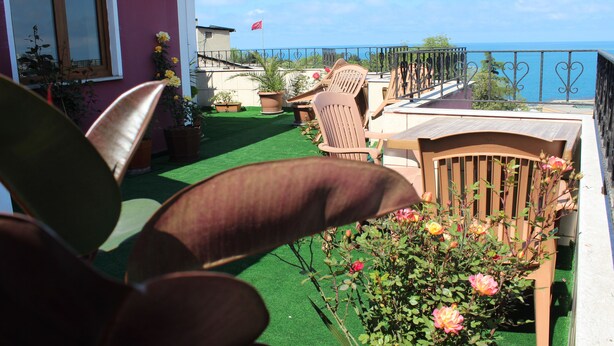 A balcony with a view of the sea, potted plants, and outdoor furniture. - Nazar Hotel (Trabzon)
