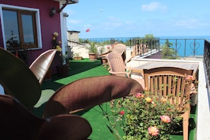 A balcony with a view of the sea, potted plants, and outdoor furniture. - Nazar Hotel (Trabzon)