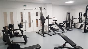 A gym with various exercise equipment including benches, weight machines, and free weights.