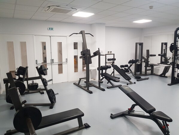 A gym with various exercise equipment including benches, weight machines, and free weights.