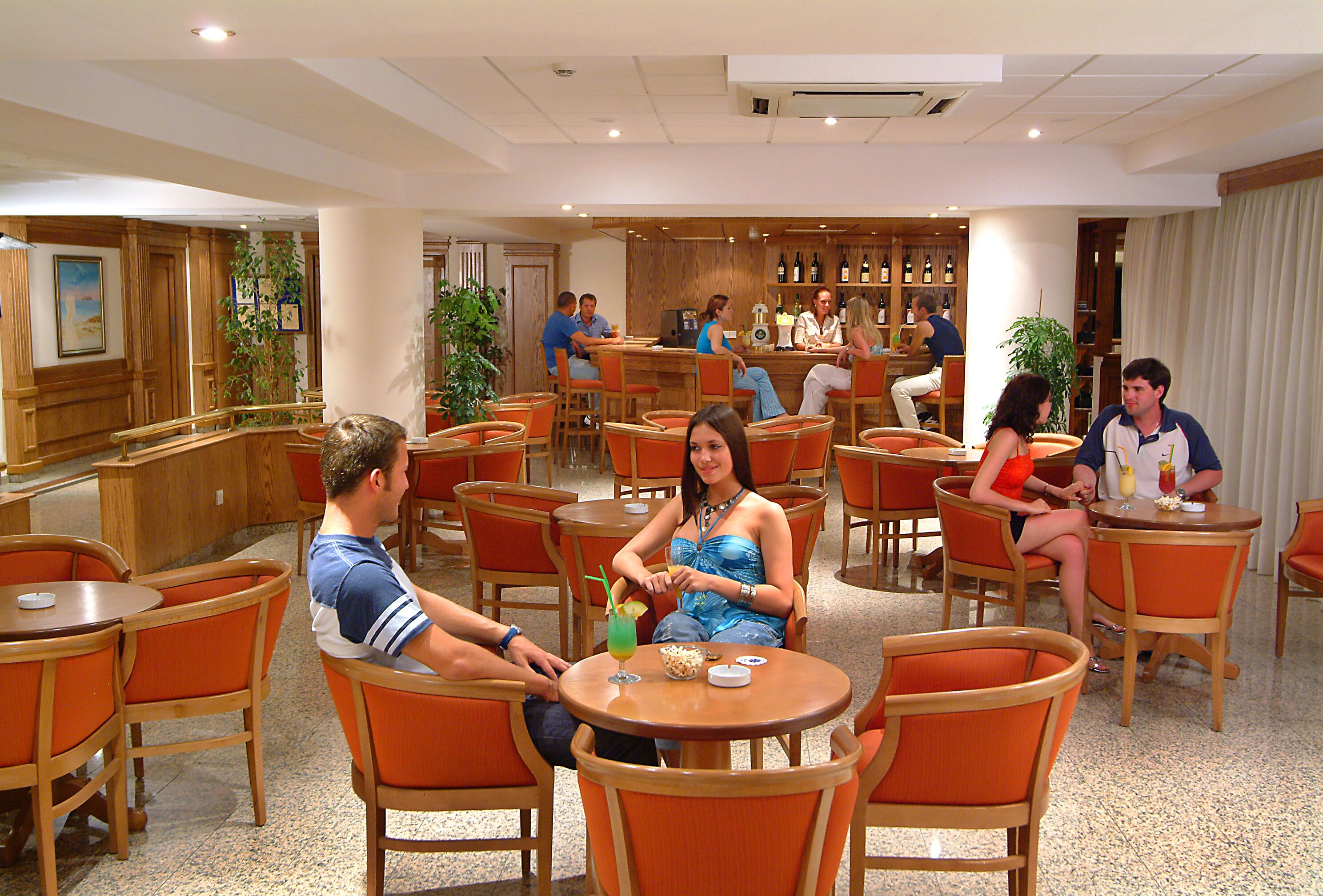 Um saguão de hotel com várias áreas de estar, um bar e uma mesa de recepção.