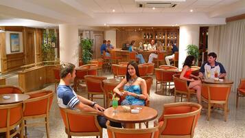 Un vestíbulo de hotel con varias zonas de estar, un bar y un mostrador de recepción.