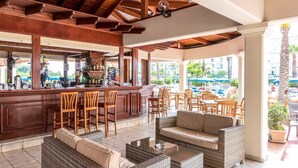 Eine Bar mit Holzmöbeln, einer Theke und Blick auf den Pool.