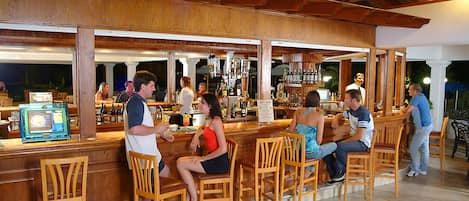 A bar area with wooden furniture and a counter displaying various bottles.