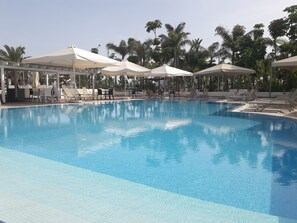 A clear swimming pool with lounge chairs and umbrellas, surrounded by palm trees. - La Casa Di Napa (Ayia Napa)