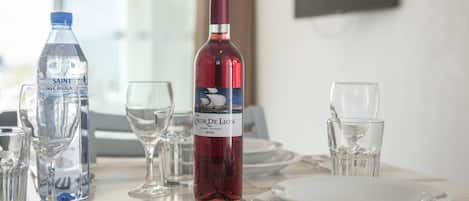 Una mesa para comer dispuesta con copas de vino, una botella de vino tinto y una botella de agua.