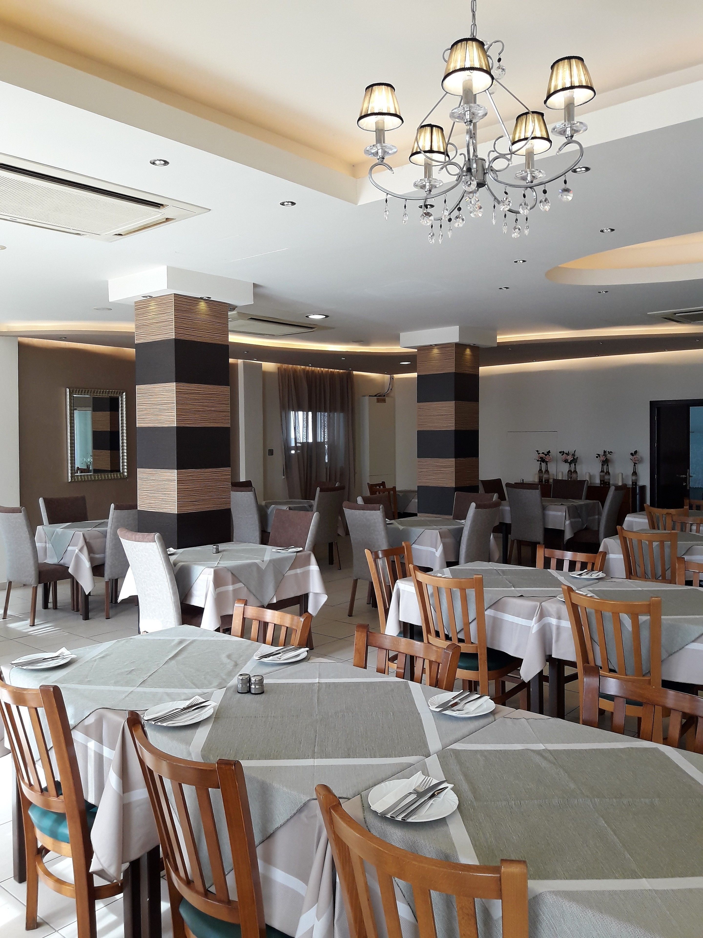 Ein Restaurant mit mehreren Tischen, Stühlen und einer Kristallleuchter.