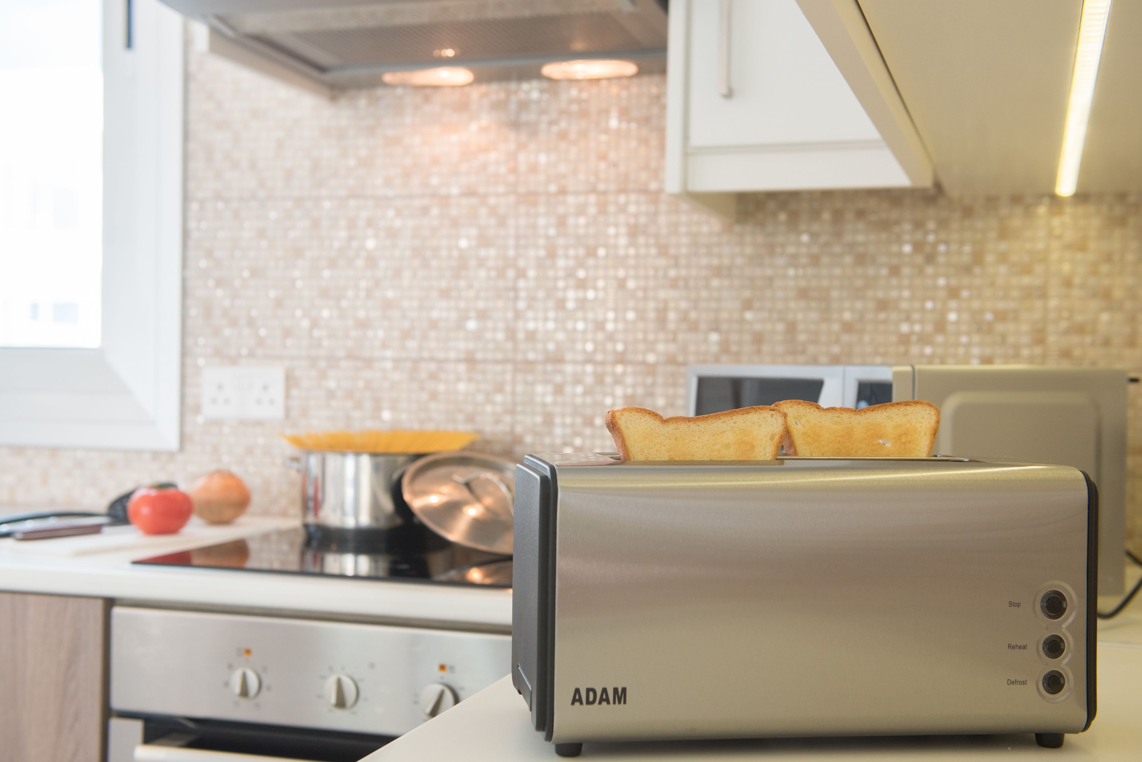 A kitchen with a toaster on the counter, a stove, and a tiled backsplash.