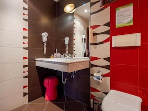 Une salle de bain moderne avec un lavabo, deux sèche-cheveux, des toilettes rouges et une poubelle.