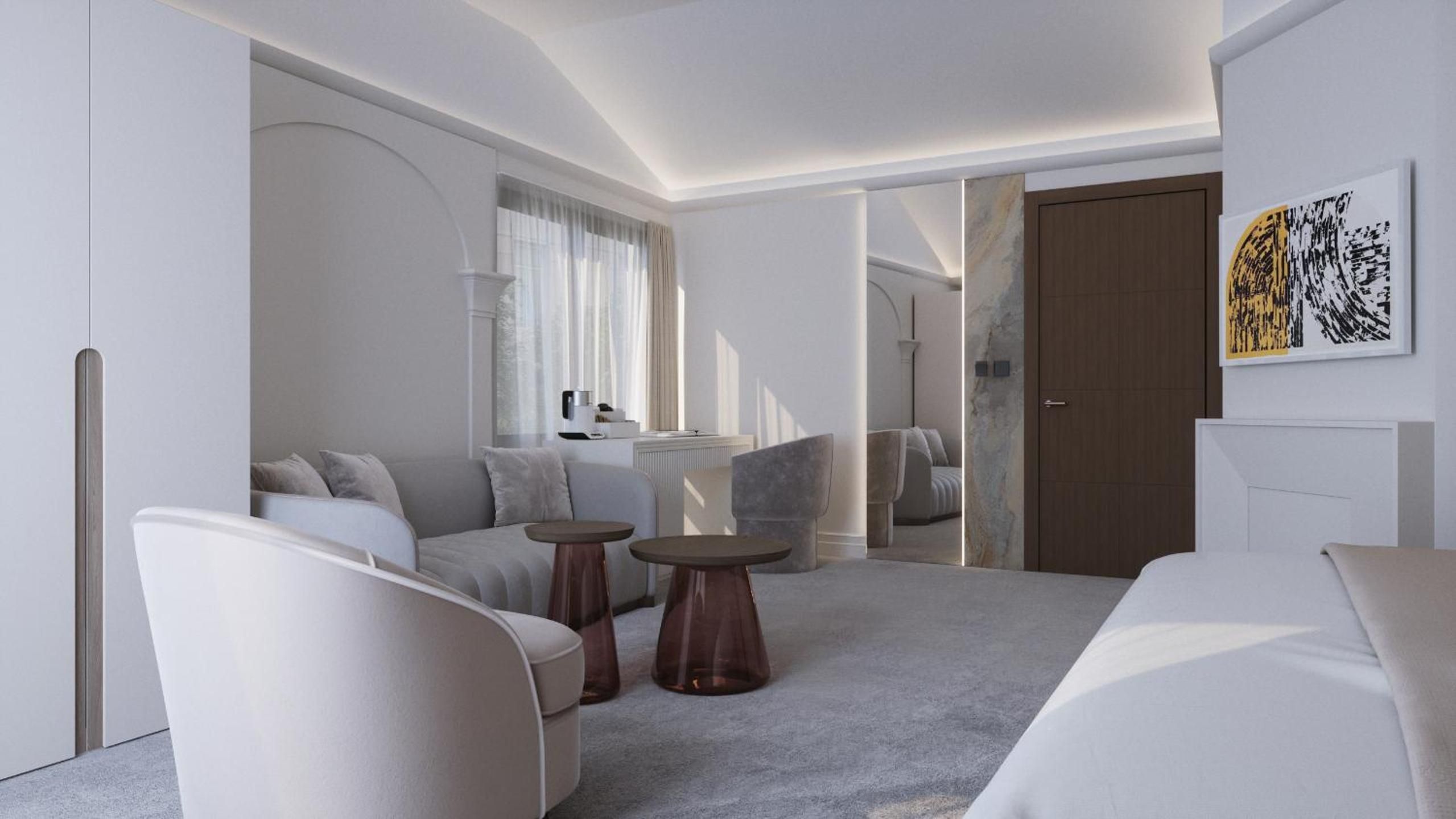 A modern hotel room with a sofa, two side tables, a bed, and a door leading to another room.