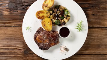 A plate with a steak, roasted potatoes, and a vegetable medley, served on a wooden table.