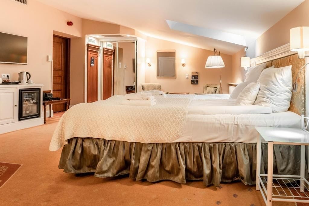 A hotel room with two beds, a desk with a lamp, a wardrobe, and a television.