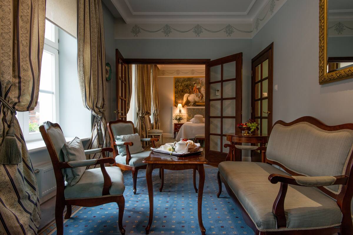 A traditional room with a blue patterned carpet, wooden furniture, and a painting on the wall.