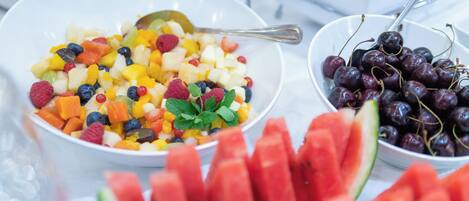 A buffet table with bowls of fruit salad and cherries.