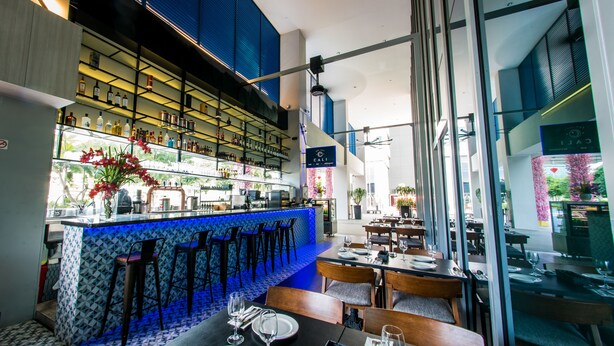 Un restaurante con zona de bar, diversas opciones de asientos y vistas al exterior.