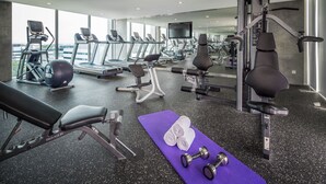 Un gimnasio moderno con cintas de correr, elípticas, un banco y equipo de pesas.