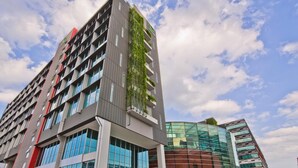 Un moderno edificio de gran altura con varios pisos, ventanas amplias y fachada de vidrio.