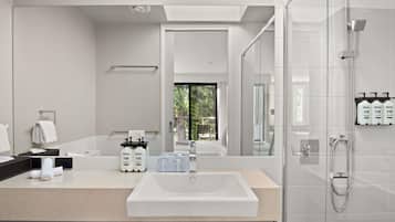 Un baño moderno con un espejo grande, un lavabo y una ducha con cerramiento de vidrio.