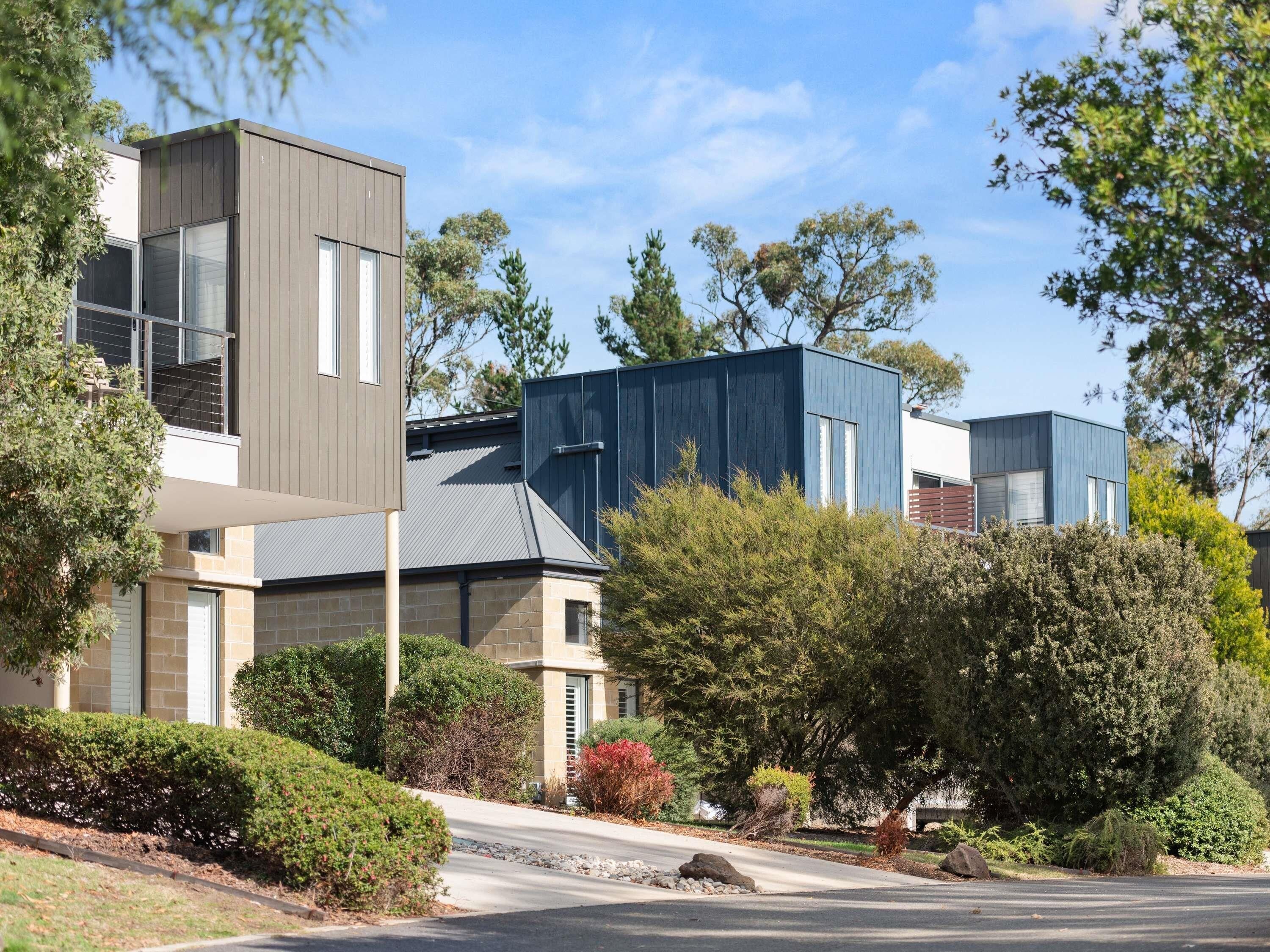 A modern residential building with a flat roof, large windows, and a mix of brick and siding materials.