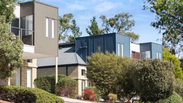 A modern residential building with a flat roof, large windows, and a mix of brick and siding materials.