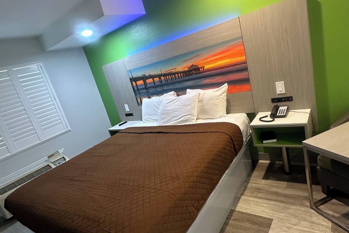 Quarto de hotel com cama, escrivaninha e telefone.