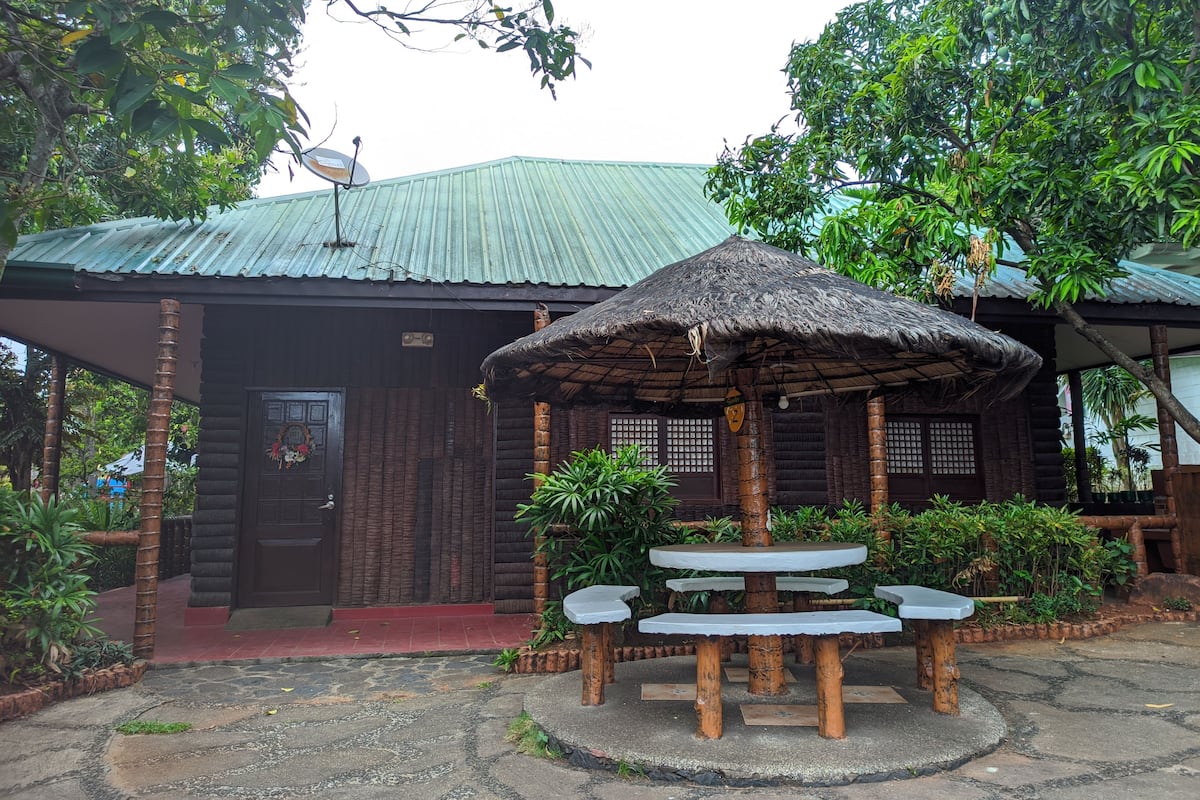 A rustic wooden building with a thatched roof and a satellite dish.