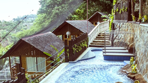 Ein Thermalgebiet mit Holzstegen, einem Pool und einem kleinen Wasserfall.