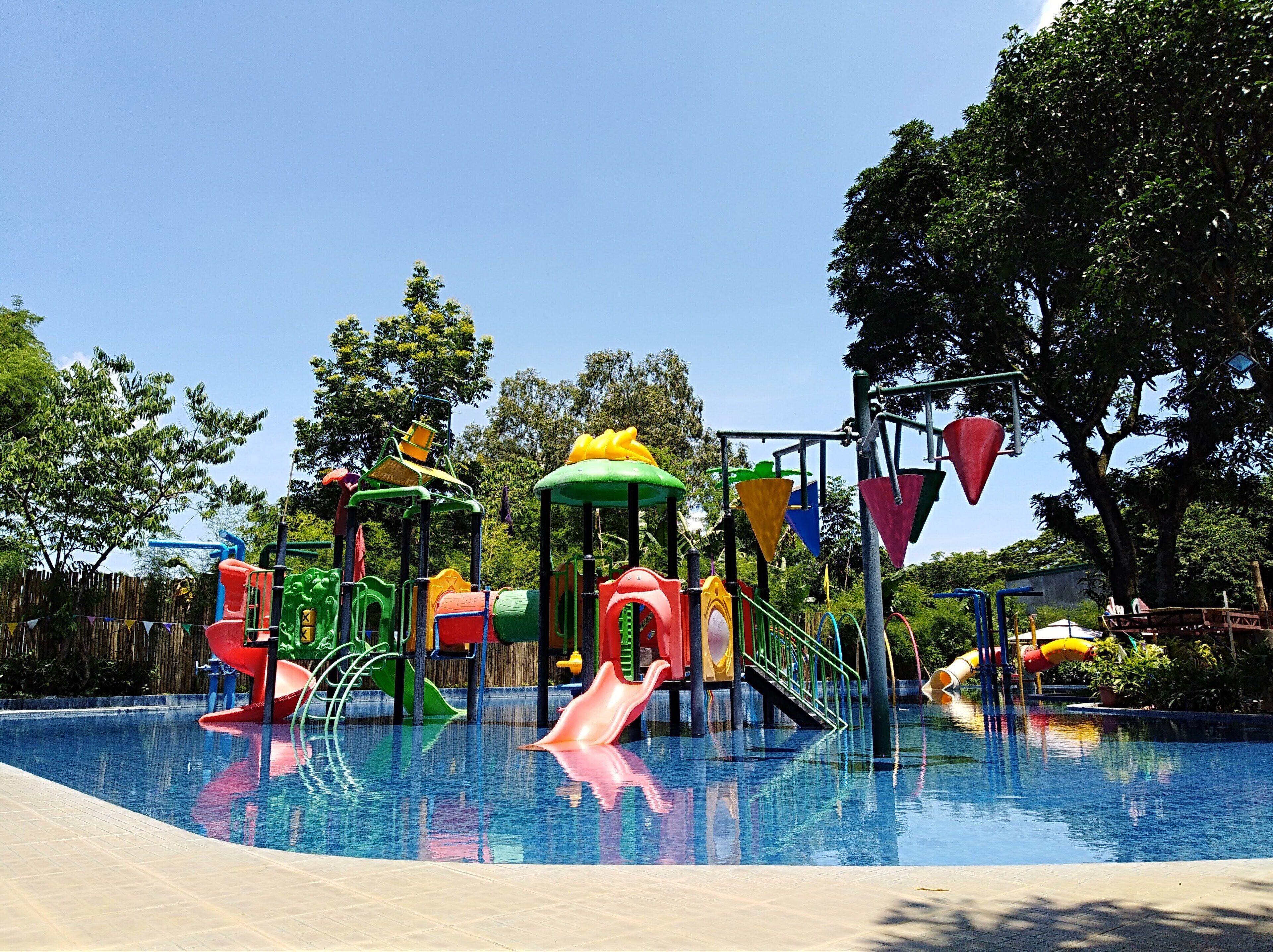 A children's play area with slides and climbing structures over a pool.