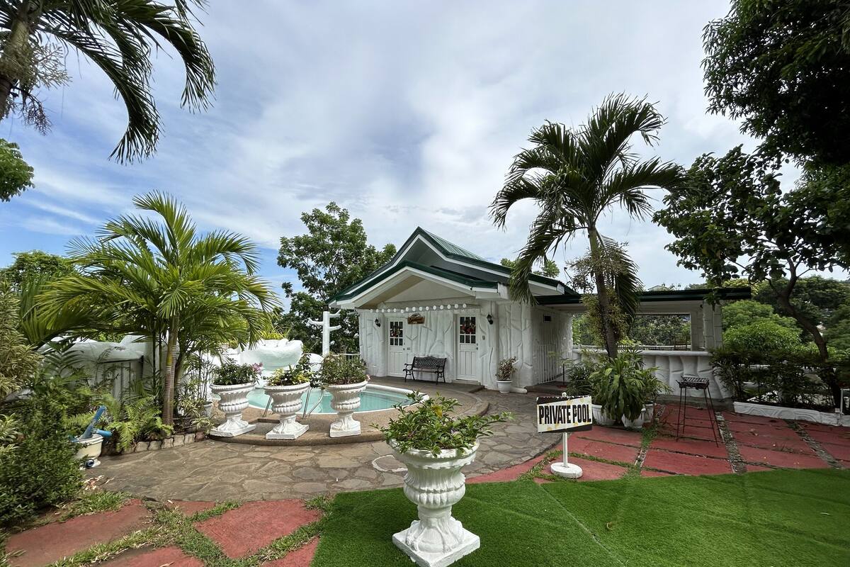 A private pool area with a white building, palm trees, and a sign indicating a private pool.