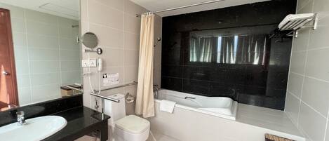 A modern bathroom with a large mirror, a bathtub, a toilet, and a vanity with a sink.