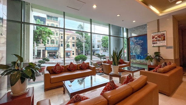 A modern lobby with leather sofas, a glass coffee table, and potted plants.
