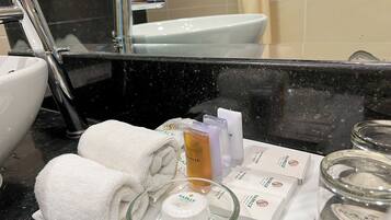 Un bagno con lavandino, specchio e articoli da toilette, tra cui asciugamani, sapone e un barattolo di vetro.