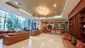A spacious lobby with a bar area, seating arrangements, and large windows offering a view of the street.