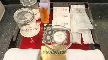 A tray with toiletries including a glass jar, a bottle, and several packaged items labeled SAPALY HOTEL - LAO CAI.