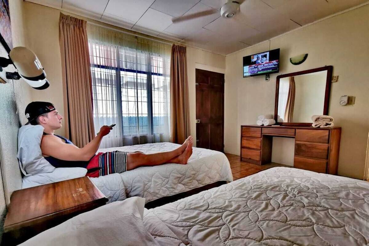 A hotel room with two beds, a TV, a desk, and a mirror.