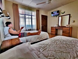 Una habitación de hotel con dos camas, televisión, escritorio y espejo.