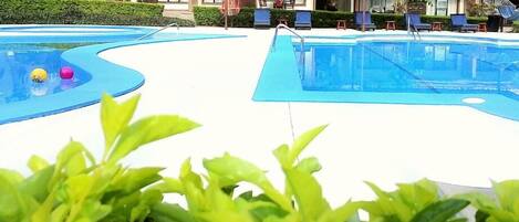 A swimming pool area with lounge chairs and a building in the background.