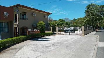 Entrada de hotel con un camino de acceso porticado, un letrero que dice 'Huites & Villas', y cielo despejado.