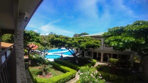 A courtyard with a swimming pool, surrounded by well-maintained hedges and trees. - Hotel & Villas Huetares (Sardinal)
