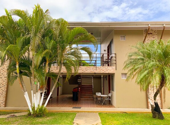 A two-story building with a covered patio area, outdoor seating, and palm trees. - Hotel & Villas Huetares (Sardinal)