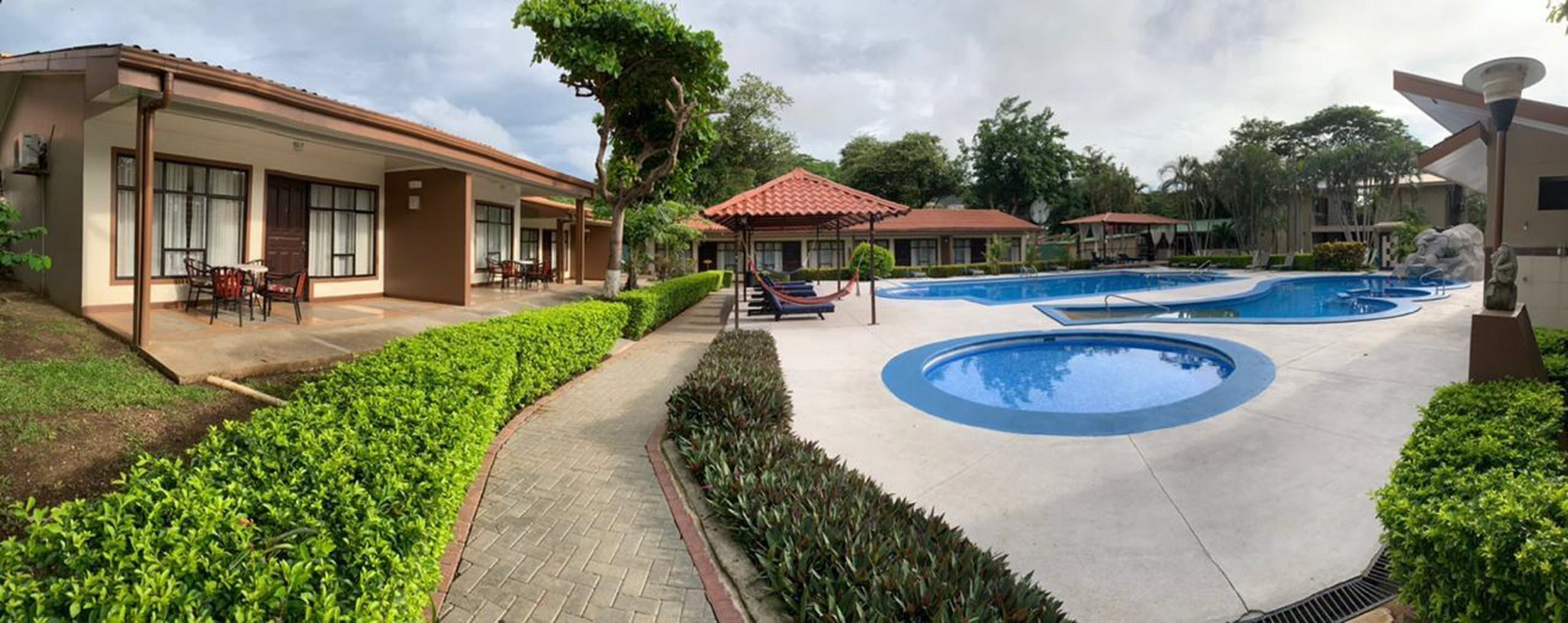A hotel with a swimming pool, covered patio, and well-maintained landscaping.